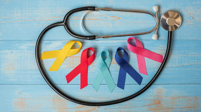 World cancer day (February 4). colorful awareness ribbons; blue, red, pink and yellow color on wooden background with stethoscpoe for supporting people living and illness. Healthcare and medicine concept